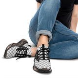 Person wearing black and white patterned sneakers with rolled-up jeans on a white background