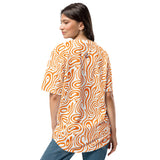 Woman wearing an orange and white patterned shirt on a white background