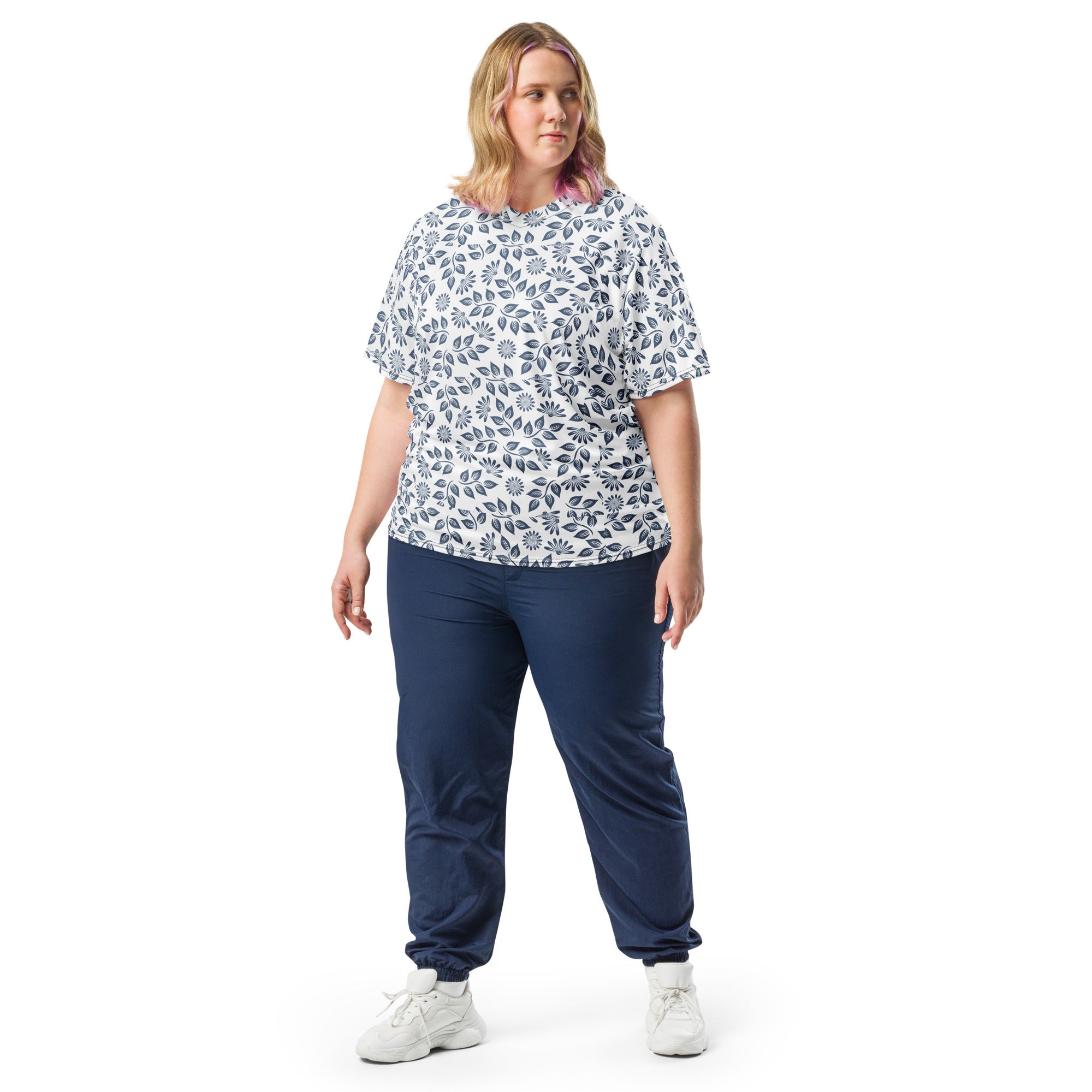 Woman wearing a patterned top and navy pants on a white background