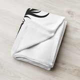 White towel with black leaf design on a light wooden surface