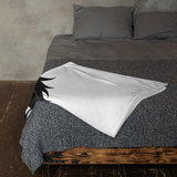 Gray textured bedspread with a white blanket and black paw print on a wooden bed frame.