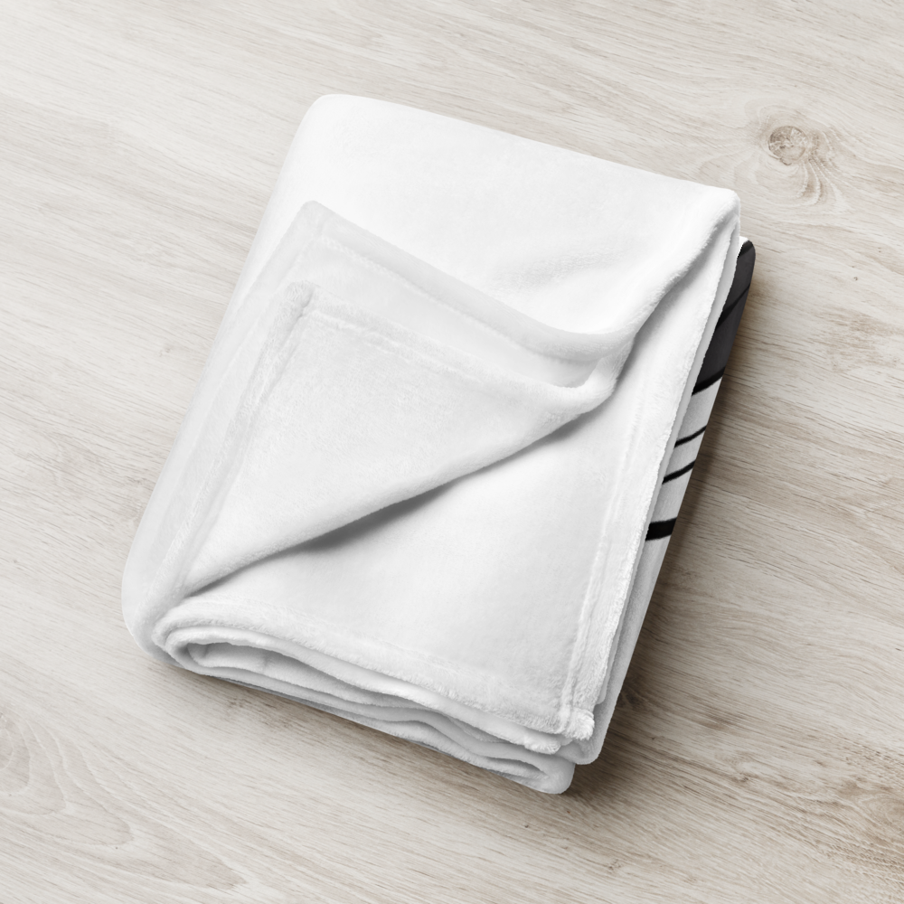 Folded white towel with black stripes on a light wooden surface