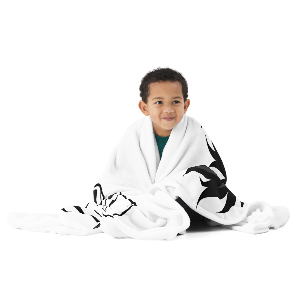 Child wrapped in a white blanket with black patterns on a white background