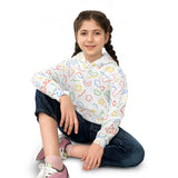 Girl wearing a colorful patterned shirt sitting on the floor with a white background