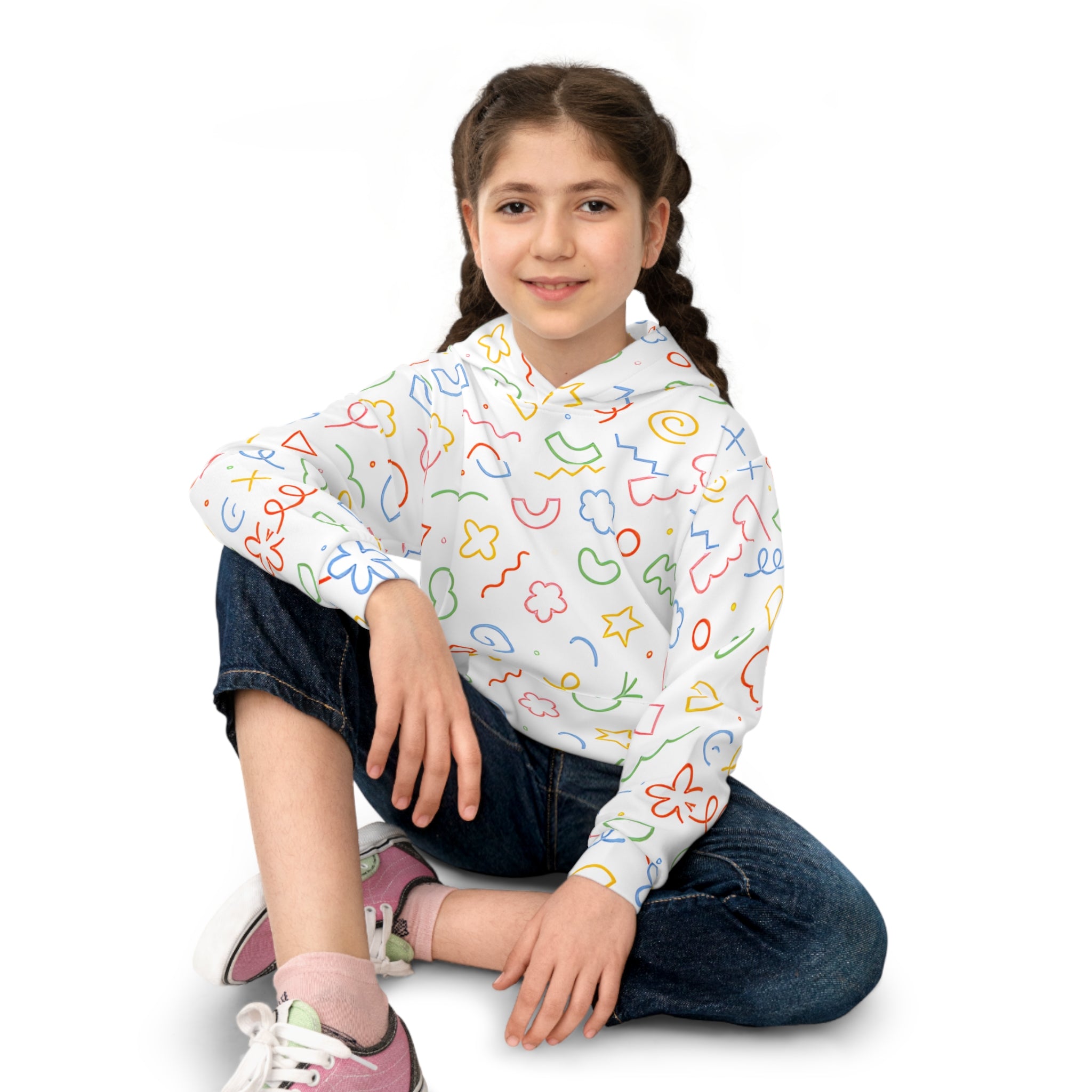 Girl wearing a colorful patterned shirt sitting on the floor with a white background