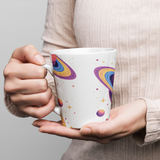 Person holding a mug with colorful designs on a plain background
