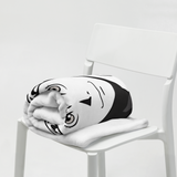 Black and white plush toy resembling a cartoon character on a white chair.